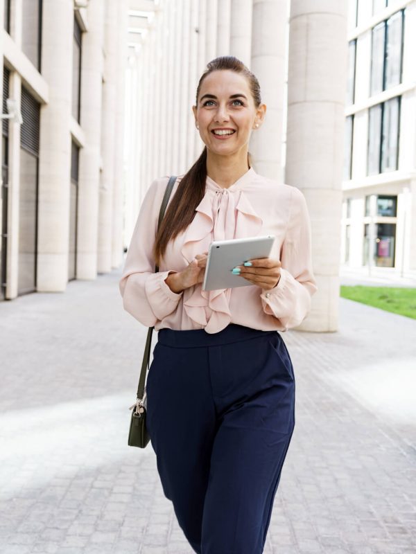 Woman walking with ipad at business location